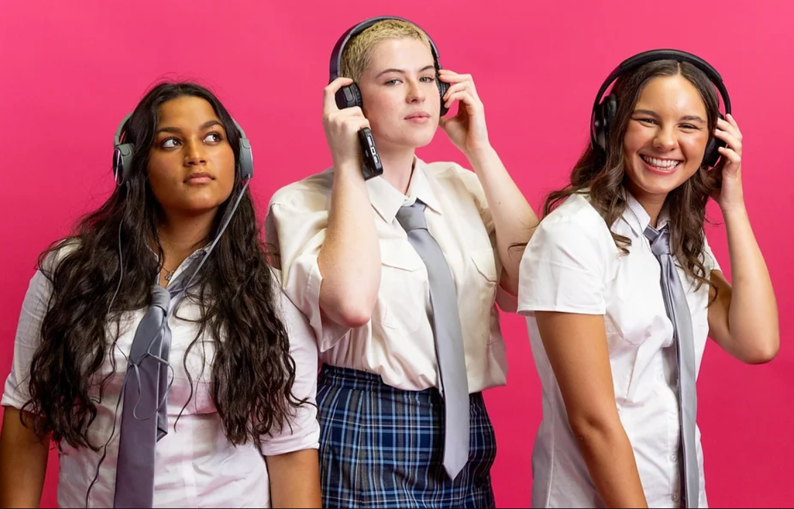 three schoolgirls listening to headphones